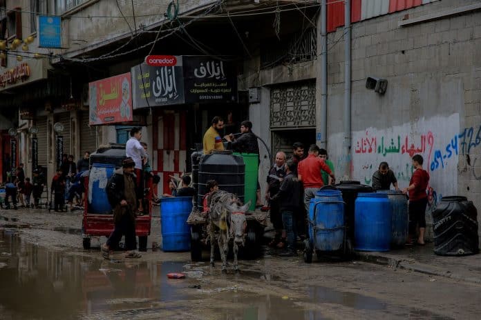 Persone riempiono l'acqua per usarla nelle loro case a causa della carenza idrica dovuta all'escalation delle ostilità in corso nella Striscia di Gaza, a Jabalia, a nord della Striscia di Gaza.