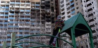Una bambina guarda gli appartamenti bruciati, in piedi su un campo da gioco nel cortile del condominio che ha subito un bombardamento la mattina del 7 febbraio 2024, a Kiev, Ucraina.