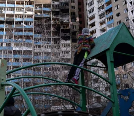 Una bambina guarda gli appartamenti bruciati, in piedi su un campo da gioco nel cortile del condominio che ha subito un bombardamento la mattina del 7 febbraio 2024, a Kiev, Ucraina.
