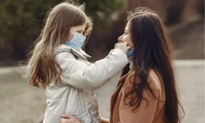 Moeder en dochter dragen mondmasker tegen COVID-19