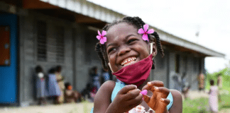 Een jong meisje in Ivoorkust is blij dat ze terug naar school mag nadat het gesloten was door COVID-19.
