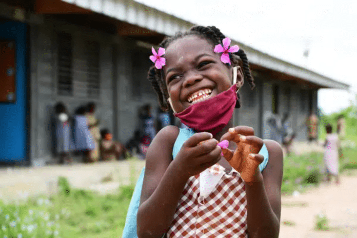 Een jong meisje in Ivoorkust is blij dat ze terug naar school mag nadat het gesloten was door COVID-19.