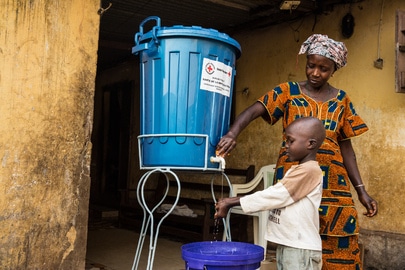 Mother washing the child’s hands in Guinea with chlorine-treated water to prevent getting infected with Ebola. UN Photo:Martine Perret