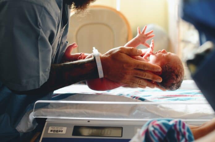 En nyfødt baby blir holdt av helsepersonell
