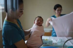Nyfødt baby innpakket i rosa teppe