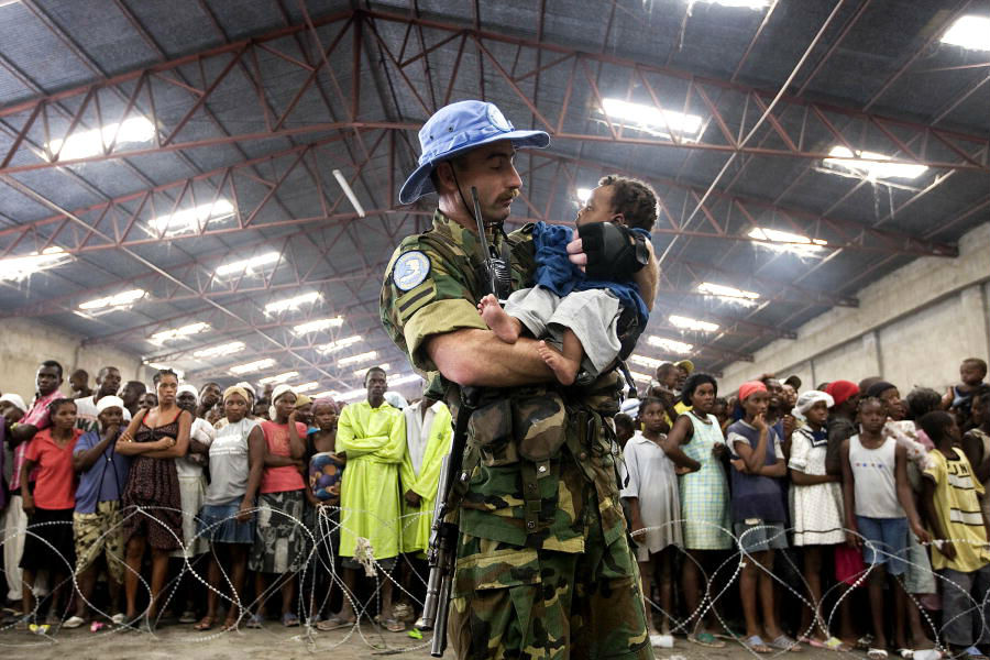 Um funcionário da Missão de Estabilização das Nações Unidas no Haiti (MINUSTAH) agarra ao colo uma das vítimas mais jovens da tempestade tropical 