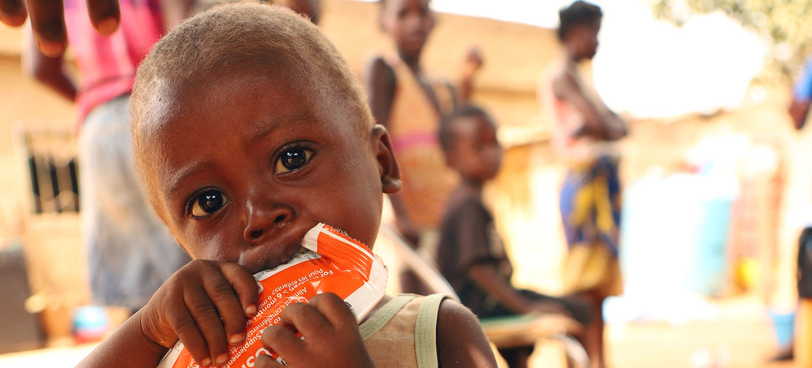 Criança de dois anos come uma pasta nutricional depois de ser testada para desnutrição em Angola