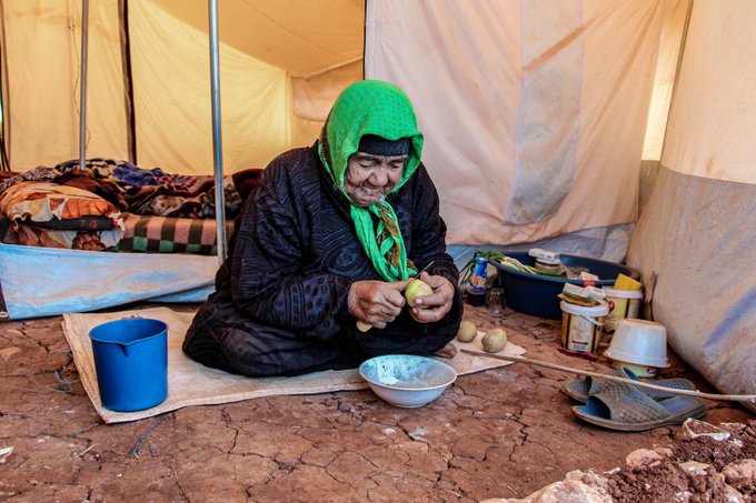 Gammal kvinna i tält i flyktingläger
