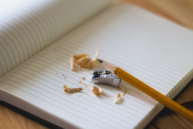 vässad penna, pennvässare och skräp på en skrivbok