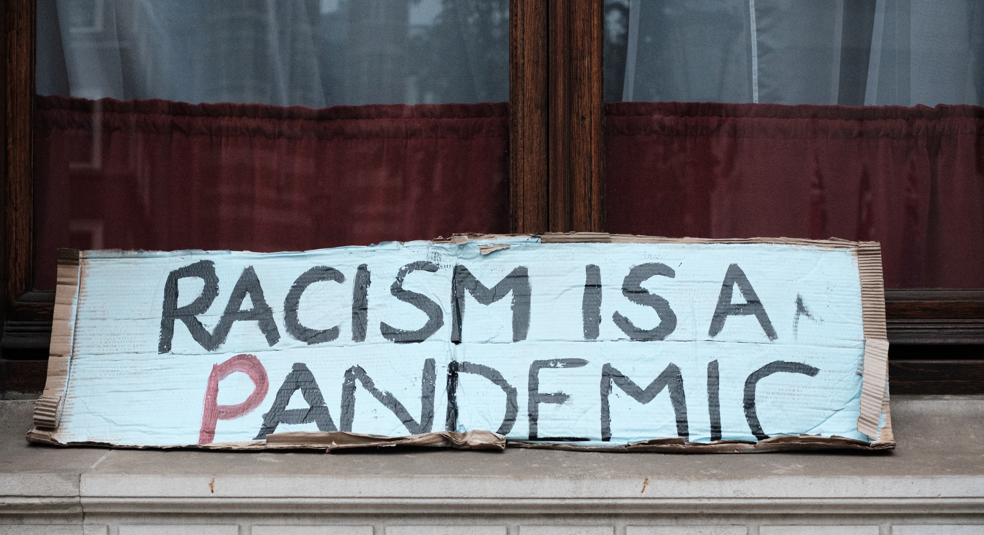En vit skylt där det står racism is a pandemic