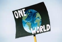 En skylt med texten one world och en bild på vår planet