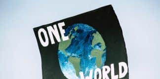 En skylt med texten one world och en bild på vår planet