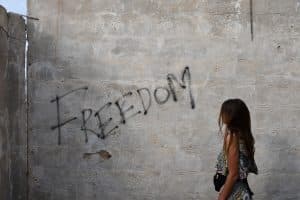 En flicka som betraktar texten Freedom sprayad på en husvägg