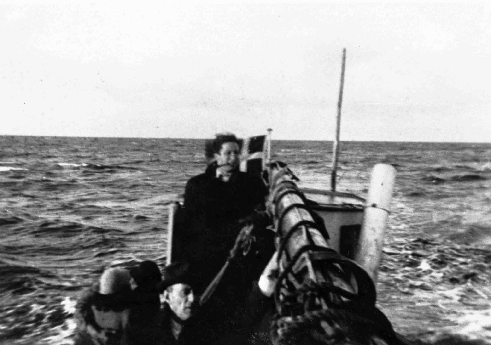 Ett svartvitt foto på en man som står i en båt till havs. 