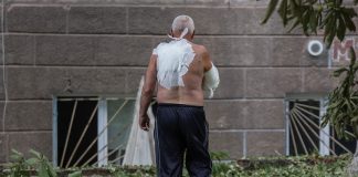 En vithårig man med bandage på ryggen och armen utan skjorta bakifrån.