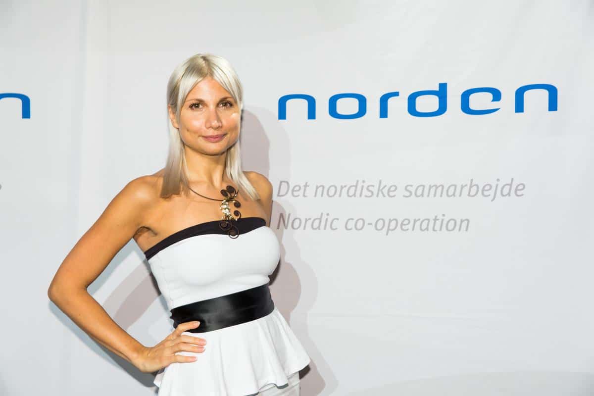 En blond kvinna i klänning som poserar framför texten Norden