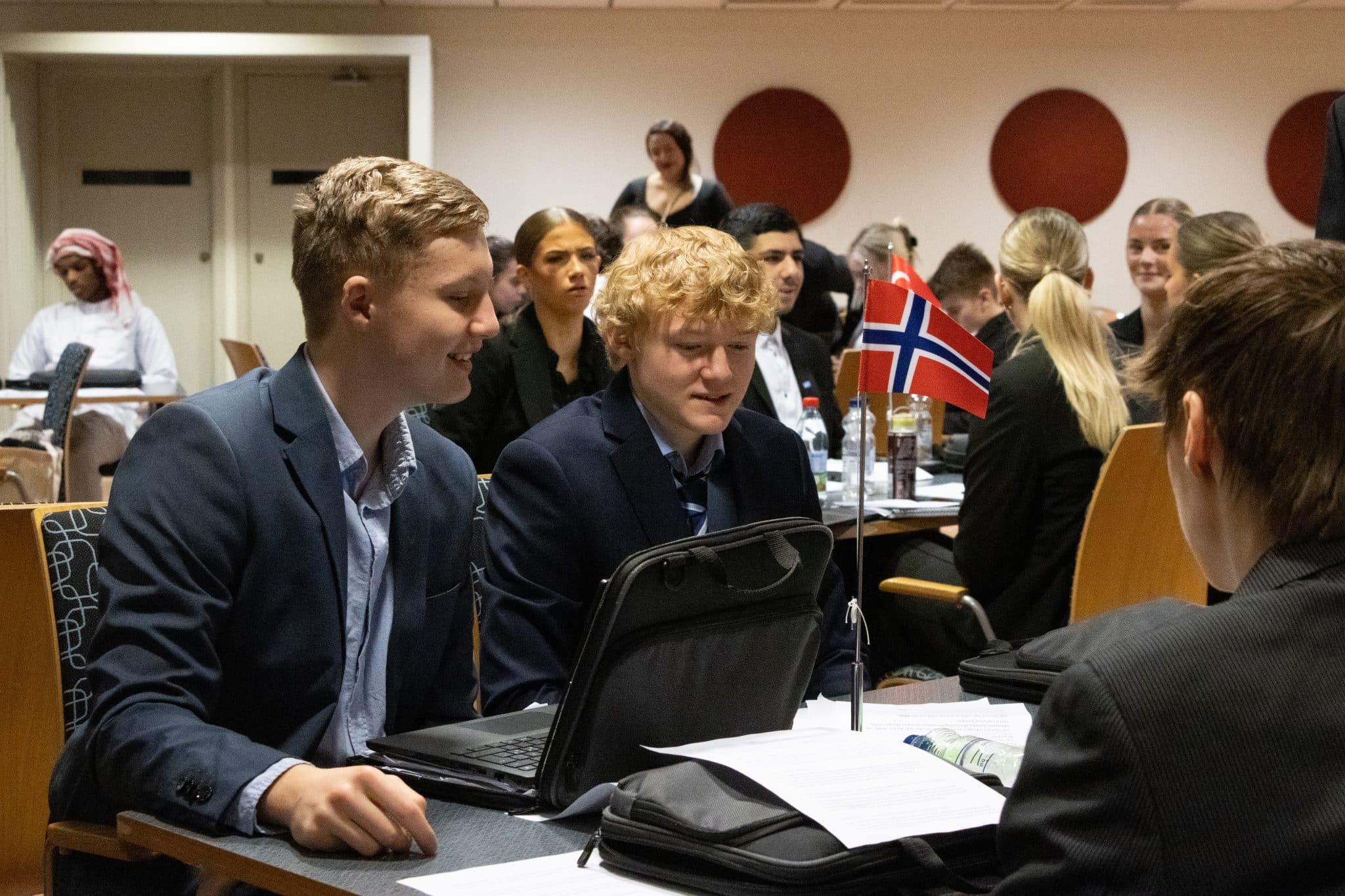 En grupp elever runt ett bord och Norges flagga i mitten.