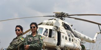 Två kvinnor i fredsbevararuniform som står framför en helikopter