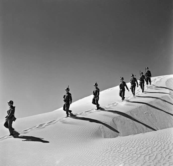 Militärer som går ner för en sanddyn.