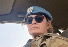 En kvinna i uniform med FNs logo på mössan