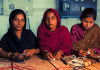 Tre flickor som sitter vid ett bord med allvarliga miner
