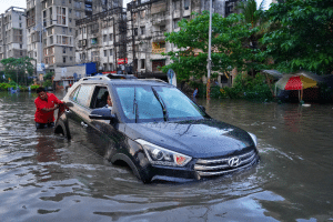 En bil på en väg som är nästan täckt av vatten på grund av översvämningar
