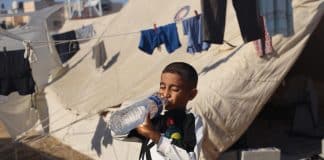 En pojke som dricker ur en flaska vatten