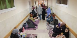 Familjer som sitter eller ligger på madrasser i en korridor