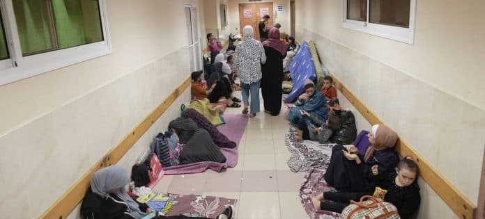 Familjer som sitter eller ligger på madrasser i en korridor