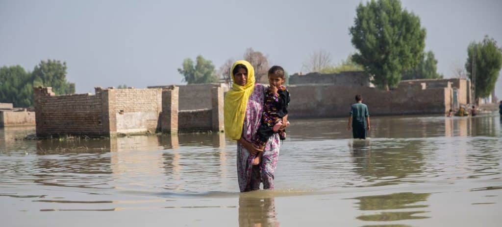 En kvinna som bär ett barn på en översvämmad plats