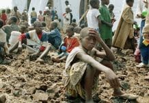Barn som sitter på jordig mark i anspråkslösa förhållanden