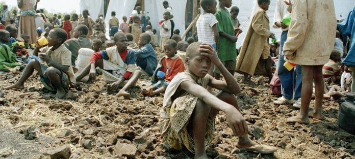 Barn som sitter på jordig mark i anspråkslösa förhållanden