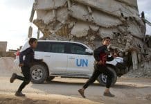 Två barn som springer framför en bil där det står UN