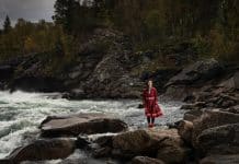 En kvinna i samisk klädsel som står vid vatten.