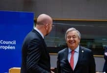Two men talking in an official setting, one is laughing