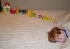 Ett barn som sover i en säng och bredvid honom finns en lång rad leksaker