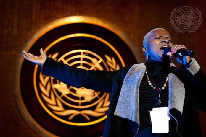 En man som sjunger på en scen med FNs logo i bakgrunden