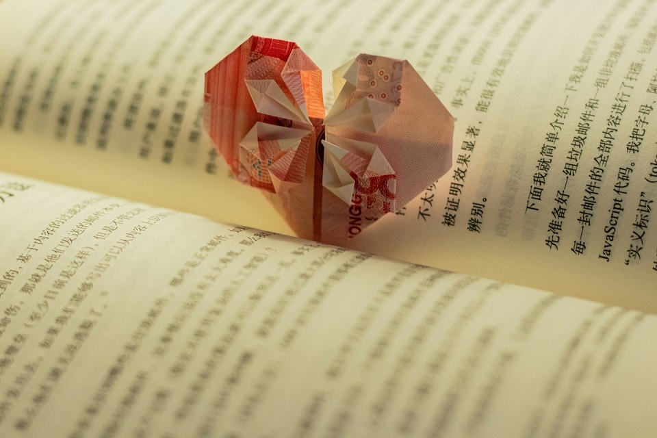 Kinesiska tecken i en uppslagen bok och ett origami hjärta