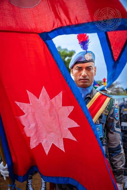 En man i militär klädsel som står bakom en flagga