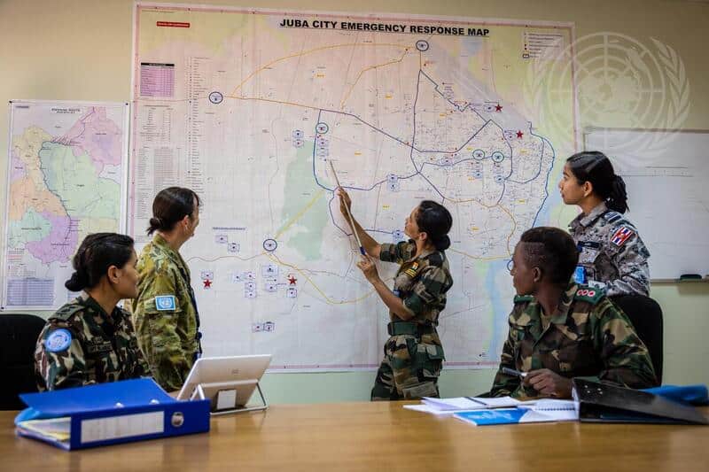 En grupp kvinnor i militär klädsel som står vid en karta
