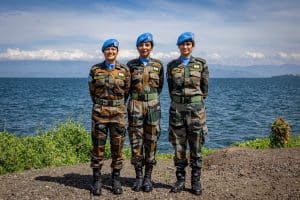 Tre kvinnor i militär klädsel vid vatten