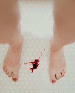 Två fötter och blod på golvet