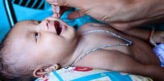 En baby som får flytande vaccin genom munnen
