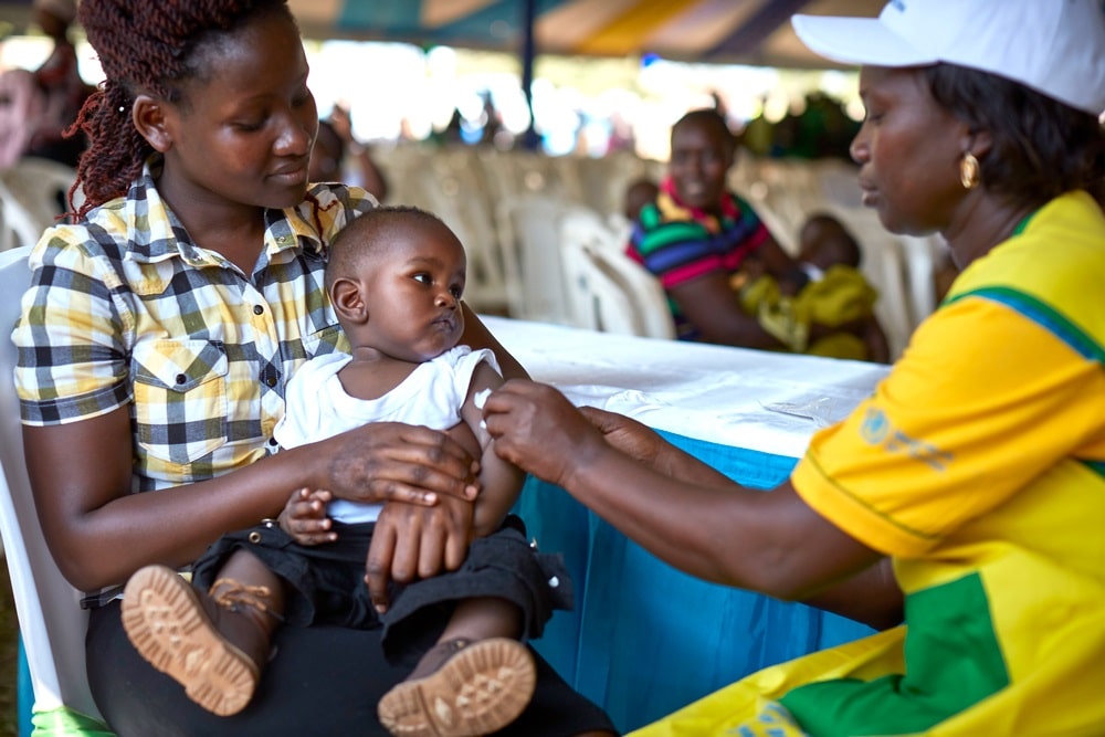 Ett barn i en kvinnas famn som får ett vaccin